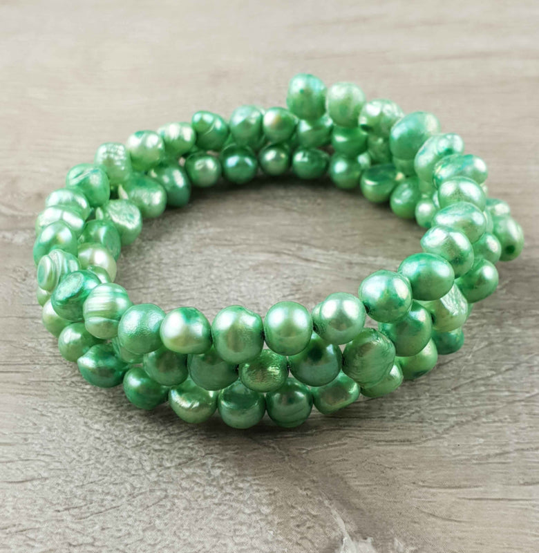 Zoetwater parel wikkelarmband met groene parels liggend op hout | Zen Green