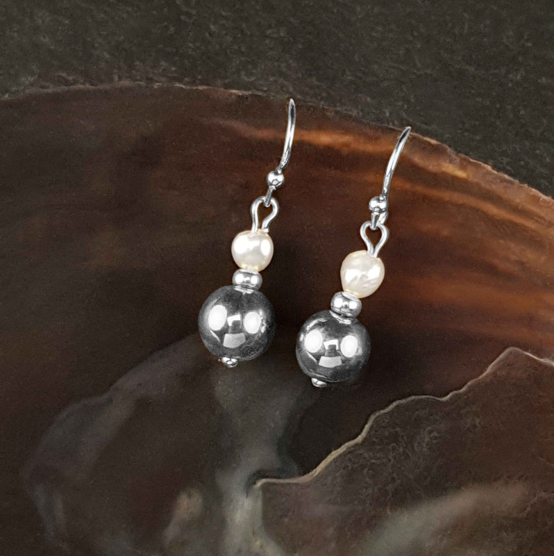 witte zoetwater parel oorbellen met zilveren edelsteen hematiet liggend in schelp vooraanzicht | Bold Silver Pearl Hematite
