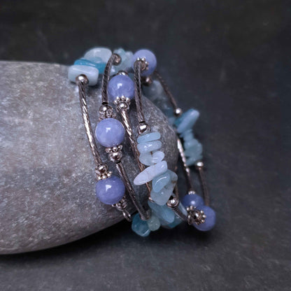Blauw edelstenen wikkelarmband met aquamarijn en aventurien liggend tegen sten